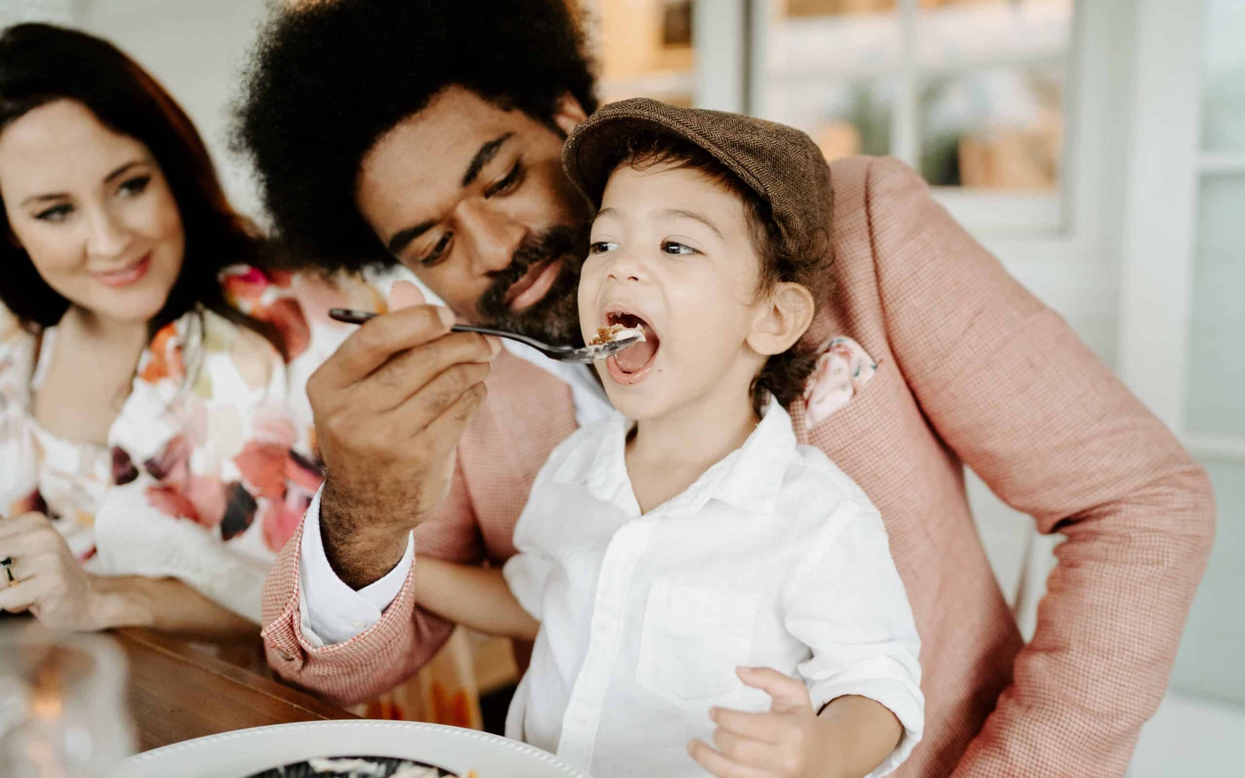 Cute family with dad feeding son dessert